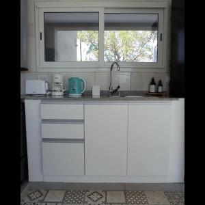 eine weiße Küche mit einem Waschbecken und einem Fenster in der Unterkunft COMPLEJO LA ISLA MAR CHIQUITA in Balneario Mar Chiquita
