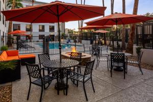 um pátio com mesas e cadeiras com guarda-sóis vermelhos em Hampton Inn Phoenix - Biltmore em Phoenix