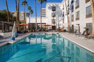 uma piscina com cadeiras e guarda-sóis ao lado de um edifício em Hampton Inn Phoenix - Biltmore em Phoenix