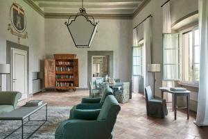 a living room with green couches and a table at COMO Castello Del Nero in Tavarnelle in Val di Pesa