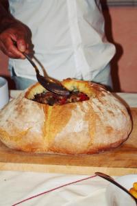 a person holding a spoon in a loaf of bread at Agriturismo U' Casinu dà Scala in Campora San Giovanni