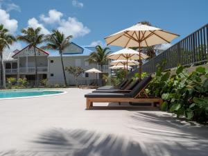 eine Reihe von Liegestühlen mit Sonnenschirmen neben einem Pool in der Unterkunft Appartement Orient Bay-Ti Paradise in Saint Martin