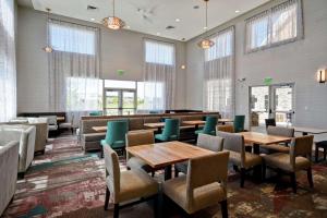 uma sala de jantar com mesas, cadeiras e janelas em Homewood Suites By Hilton Salt Lake City Airport em Salt Lake City