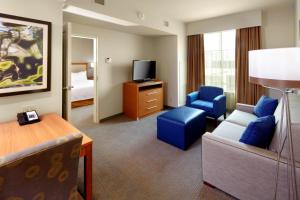 Homewood Suites by Hilton Pittsburgh Airport/Robinson Mall Area في Moon Township: غرفة في الفندق تحتوي على أريكة وكراسي وتلفزيون