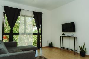 a living room with a couch and a flat screen tv at Che Suites Tulum in Tulum