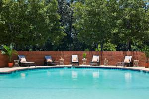 a swimming pool with chairs and a brick wall at Doubletree By Hilton Atlanta Perimeter Dunwoody in Atlanta