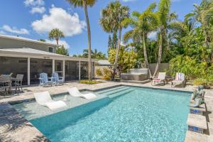 a swimming pool with chairs and a house with palm trees at Mermaids Oasis - 315 in Bailey Hall