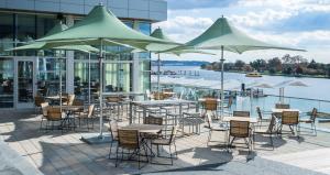 un patio al aire libre con mesas, sillas y sombrillas en Canopy By Hilton Washington DC The Wharf en Washington