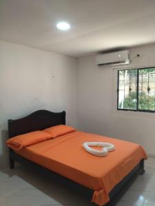 1 dormitorio con 1 cama con manta naranja y ventana en Hostal Almirante, en Ríohacha