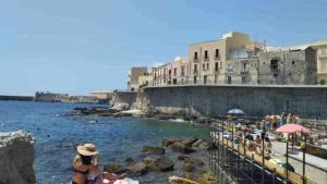 a group of people sitting on the rocks near the water at Casa Lucia Ortigia in Syracuse