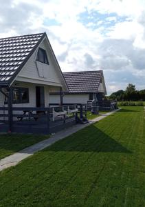 Ein weißes Haus mit einem Grasfeld daneben. in der Unterkunft "Chatki Nad Zalewem" Kluczbork in Ligota Zamecka