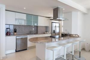 a kitchen with white cabinets and a counter with stools at Marbella Juan Dolio Beachfront in Juan Dolio