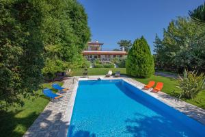 a swimming pool with chairs and a house at KORALIA MARATHON VILLA in Nea Makri