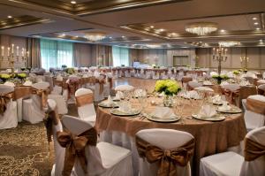 - une salle de banquet avec des tables et des chaises avec des bows dans l'établissement Hilton Greenville, à Greenville