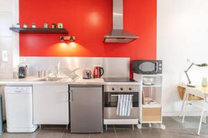 een keuken met een fornuis en een rode muur bij La loge Lyonnaise-Saxe Gambetta-Université in Lyon