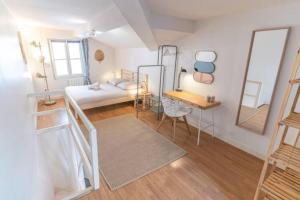 een kleine kamer met een bed, een bureau en een spiegel bij La loge Lyonnaise-Saxe Gambetta-Université in Lyon