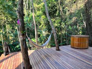 uma rede de descanso num deque de madeira na floresta em Monkey Lodge - Casa na Mata no Rio de Janeiro