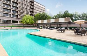 a swimming pool with tables and chairs and a building at DoubleTree by Hilton Hotel & Suites Houston by the Galleria in Houston