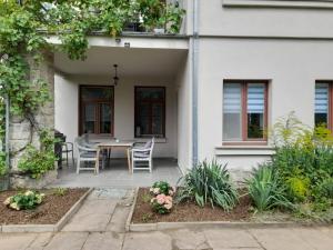 een wit huis met een tafel en stoelen op een patio bij Ferienwohnung Villa Einetal in Aschersleben