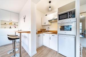 uma cozinha com armários brancos e um balcão em Le petit Massena-cosy 2 pers balcon- Part Dieu em Lyon