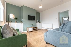 een woonkamer met 2 banken en een tv bij Cosy 3 Bedroom house in Wigan in Bickershaw