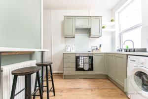 a kitchen with green cabinets and two bar stools at Cosy 3 Bedroom house in Wigan in Bickershaw