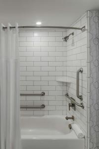 een badkamer met een douche en een bad met een douchegordijn bij The Kingsley Bloomfield Hills - a DoubleTree by Hilton in Bloomfield Hills