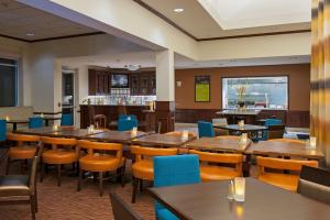a restaurant with wooden tables and chairs and a bar at Hilton Garden Inn St. Paul Oakdale in Oakdale