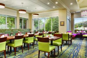 Hilton Garden Inn Niagara-on-the-Lake في نياغرا اون ذا ليك: غرفة طعام مع طاولات وكراسي ونوافذ