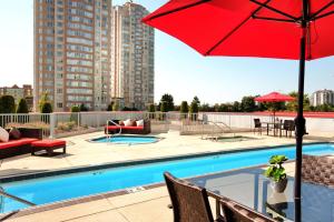 una piscina con ombrellone rosso accanto a un edificio di Hilton Vancouver Metrotown a Burnaby