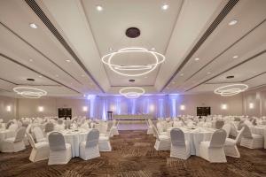 un salón de banquetes con mesas y sillas blancas y una lámpara de araña en Hilton Vancouver Metrotown en Burnaby