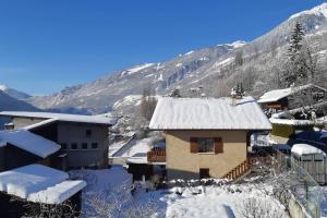ein schneebedecktes Haus mit Bergen im Hintergrund in der Unterkunft Charming apartment 12 pers, 3*, Aime-La-Plagne in Aime La Plagne