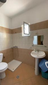 bagno con servizi igienici, lavandino e specchio di Overview Apartments Saranda a Sarandë