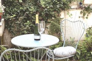 a bottle of wine sitting on a table with two chairs at Quirky City-Centre Cottage in Exeter