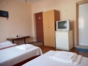 a room with two beds and a tv on a cabinet at Guest House Borisov in Shabla