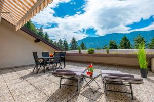 patio con mesa y sillas en el balcón en Happy Guest Apartments - Mountain Panorama Borno, en Borno