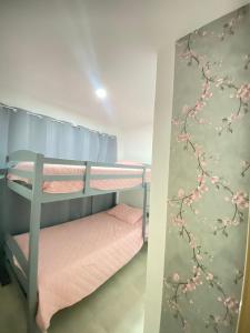 Paradise Apartment في سان سلفادور: غرفة نوم مع سريرين بطابقين مع زهور على الحائط
