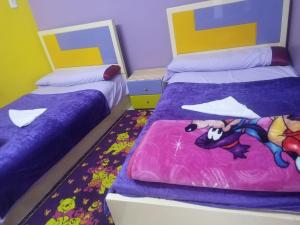 two beds in a room with purple and yellow at Fekry home in Aswan
