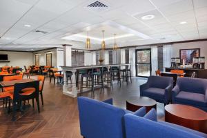 a restaurant with tables and chairs and a bar at Hampton Inn Boston/Peabody in Peabody