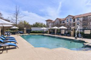ein großer Pool mit Stühlen und Sonnenschirmen in der Unterkunft Hampton Inn & Suites Legacy Park-Frisco in Frisco