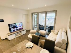 Luxury 1bedroom with Parking In Center&Large Terrace -CD3 في لوكسمبورغ: غرفة معيشة مع أريكة وتلفزيون بشاشة مسطحة
