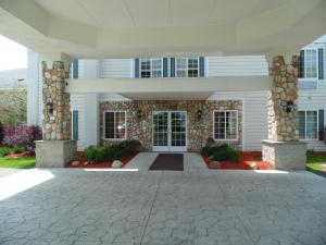 Cette grande maison blanche présente une façade en pierre. dans l'établissement American Inn and Suites Houghton Lake, à Houghton Lake