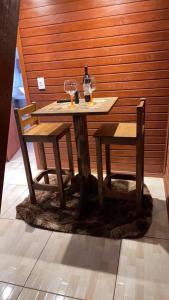 a wooden table with two chairs and a wine glass at Império Cabanas in Urubici