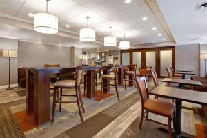 un restaurante con mesas de madera, sillas y luces en Hampton Inn Fort Wayne-Southwest, en Fort Wayne