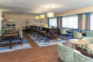 un restaurante con mesas y sillas y un bar en Hampton Inn East Lansing, en East Lansing
