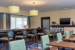 une salle à manger avec des tables, des chaises et une télévision dans l'établissement Hampton Inn East Lansing, à East Lansing