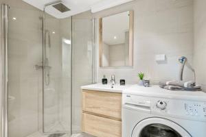 a bathroom with a washing machine and a shower at Demims Apartments Oslo Airport in Eidsvoll