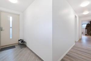 um quarto vazio com paredes brancas e pisos de madeira em Demims Apartments Oslo Airport em Eidsvoll