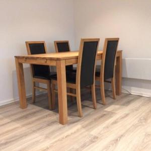 uma mesa de madeira com quatro cadeiras à volta em Demims Apartments Oslo Airport em Eidsvoll