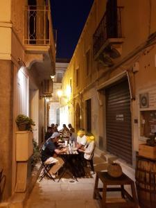 un grupo de personas sentadas en una mesa en un callejón en Casa Storico Centro en Marsala